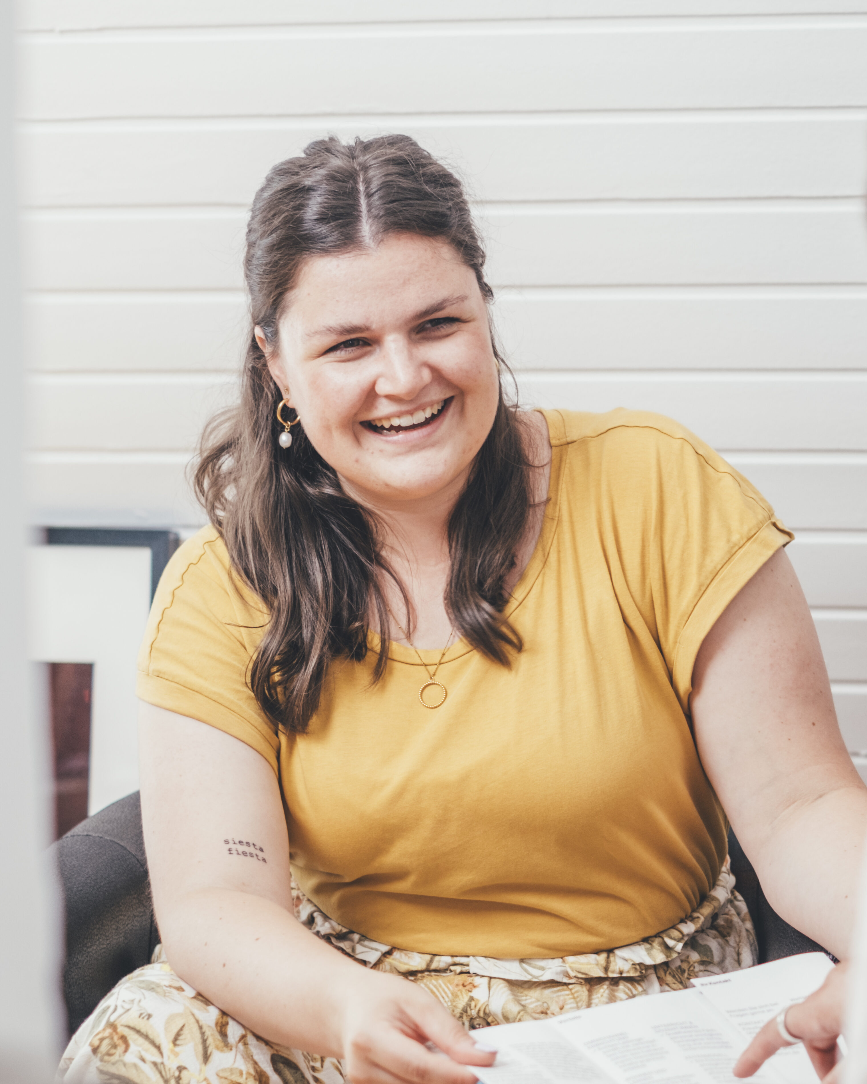 Alina Wörrmann vom Mediacampus Frankfurt sitzt lachend an einem Tisch.