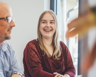 Zwei Personen unterhalten sich lächelnd miteinander am Tisch.