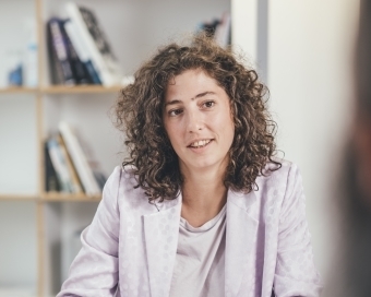 Eine Frau unterhält sich mit einer weiteren Person, die sich außerhalb der Kamera befindet.